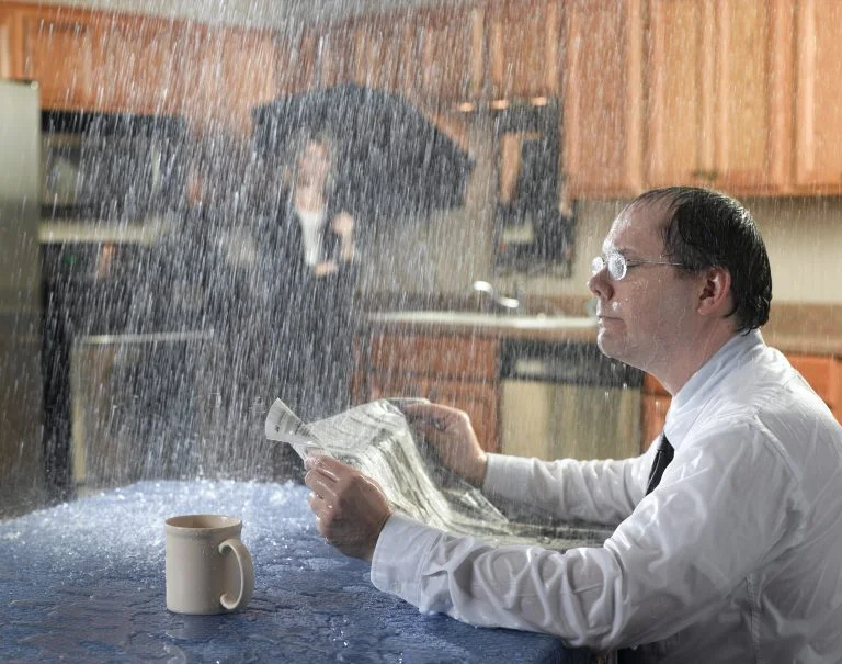 Storm damage restoration: rain pouring through a storm-damaged ceiling